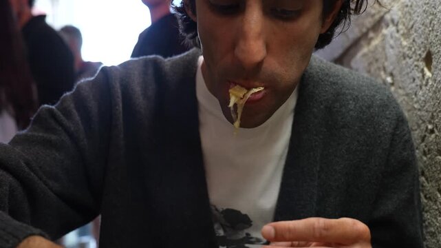 young man eating mexican tacos with cheese at a fast food chain 