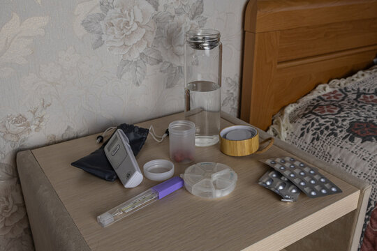 Nightstand with Medicines, Water Bottle and Medical Thermometer