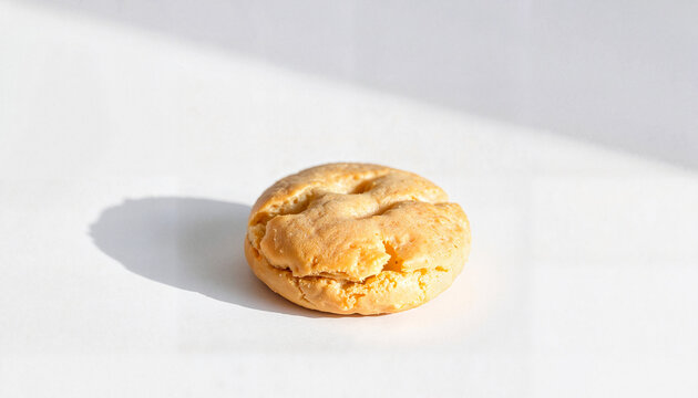 Round pastry on white surface with natural light and shadow  