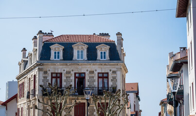 Historic european townhouse with classic architecture red shutters and tiled roof in sunny city street scene © AnastasiiaAkh