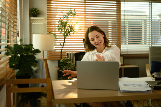 Young Caucasian woman easing tension with a stretch break, maintaining wellness during remote work at home