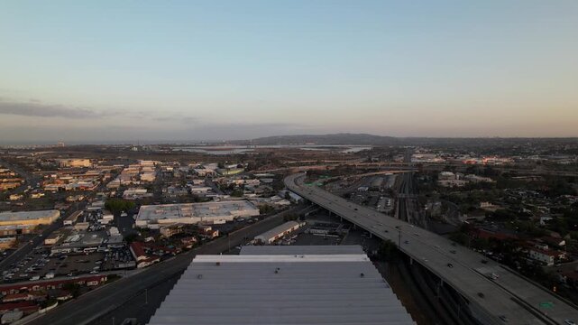 Drone flying north toward the Rosecrans exit at 6AM with Mission Bay visible in the background during sunrise.
