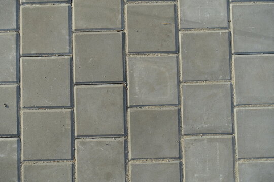 Texture of square brick-like gray concrete pavement with stack bond layout