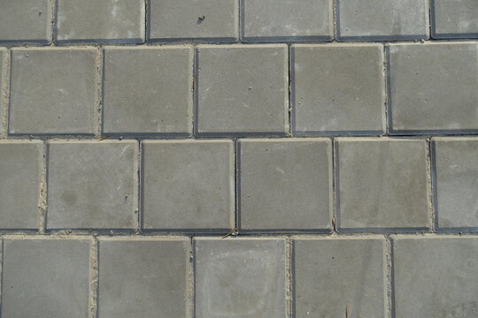 Texture of square brick-like gray concrete pavement with stack bond layout