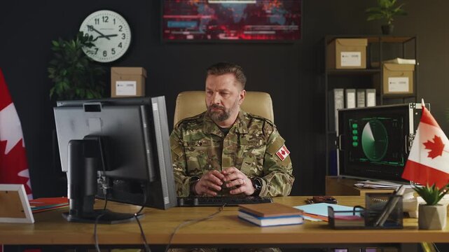 Canadian military officer focused on operational planning, typing on computer