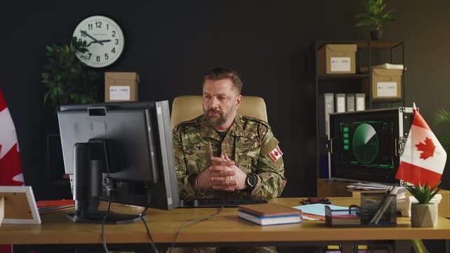 Portrait of Canadian army general typing reports while working on computer