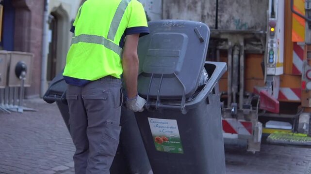 Workers are loading Trash Containers to the Municipal recycling garbage collector truck in France. Waste garbage truck.