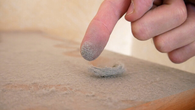 Close-up of a finger with the layer of dust from a very dusty surface