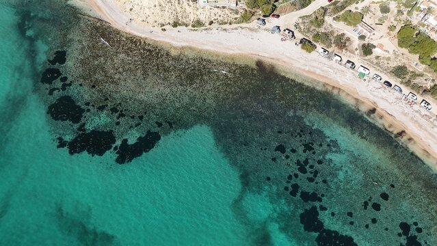 Drone shot revealing turquoise Mediterranean beach with clear seabed and pebble shore