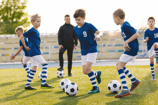 Boys on soccer football training. Young players dribble ball between training cones. Soccer summer training camp. Players on football practice session