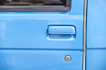 Obraz premium Close up detail of bright blue truck door handle and lock cylinder showing smooth painted metal surface conveying calm and steady mood perfect for transportation themes