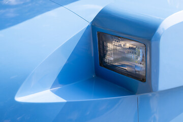 Close up of blue car popup headlight showing vintage sports classic vehicle auto design detail evoking nostalgic and happy feeling of retro driving freedom on open road © CoreRock
