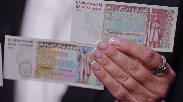 Ukrainian banknotes from different eras &mdash; a modern stylized 200000 coupon note and a historical 1,000,000 karbovanets banknote from 1995.Close-up shot of female hands.