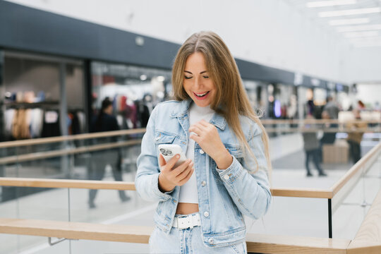Happy Woman Looking at Smartphone in Shopping Mall