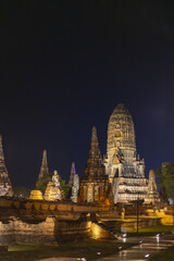 Naklejka premium Majestic ancient wat ayutthaya temple ruin illuminated at night standing peaceful under dark sky reflecting calm historical beauty offering awe inspiring sight for traveler seeking old monument