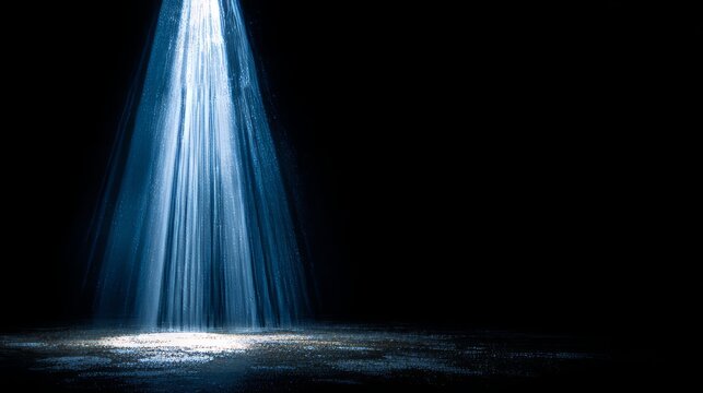 A blue spotlight beam cuts across the dark empty studio floor under moody dramatic lighting