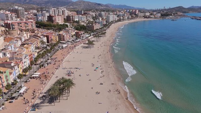 Drone flying forward over beach toward Villajoyosa colorful houses