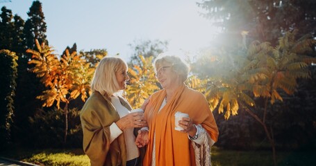 Fototapeta premium Senior women friends enjoying outdoor coffee conversation