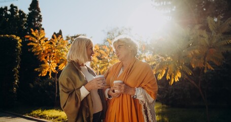 Fototapeta premium Senior friends enjoying autumn walk and coffee conversation