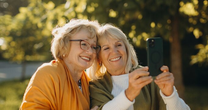 Happy senior friends smiling, taking a selfie outdoors