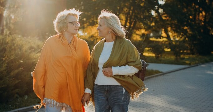 Senior women friends conversing walking outdoors in autumn