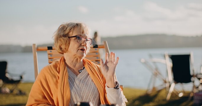Senior woman talking by lake on sunny day
