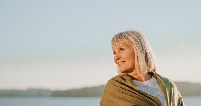 Senior woman smiling enjoying golden hour outdoors