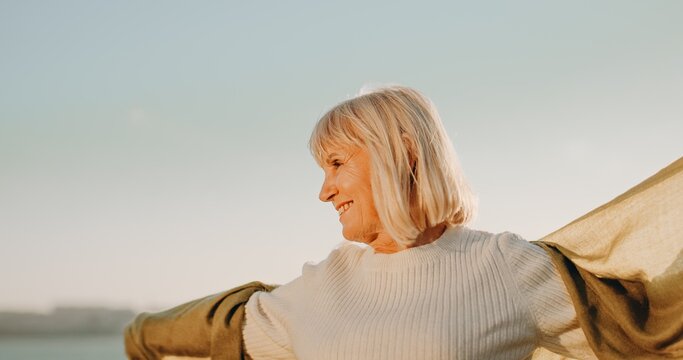Senior woman smiling with arms outstretched feeling free
