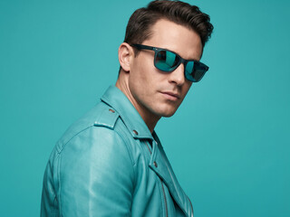 Fototapeta premium Confident Stylish Man in Turquoise Leather Biker Jacket and Mirrored Aviator Sunglasses