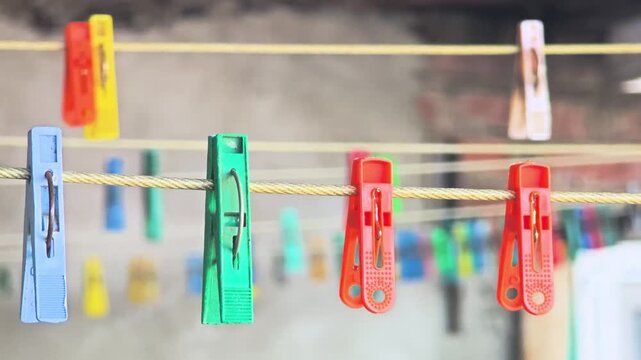 Colorful clothespins hanging on a clothesline against a blurred background. The scene captures a vibrant and practical aspect of daily life.