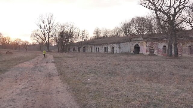 Two sisters are walking against the background of sunset and destroyed catacombs in the autumn Park.