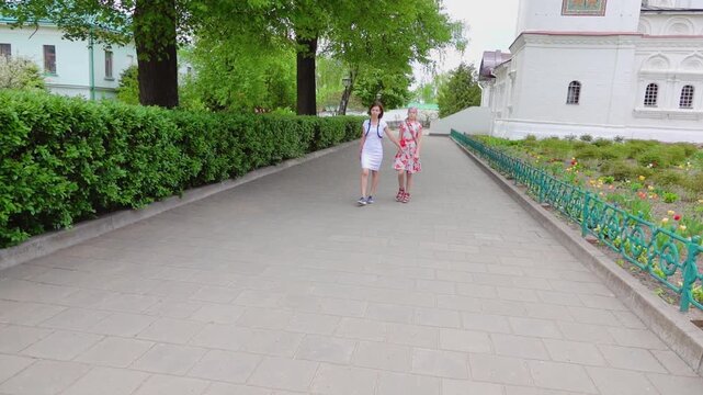 Slow Motion Two sisters are walking around the courtyard of the Borisoglebsky Kremlin in Dmitrov, Russia.