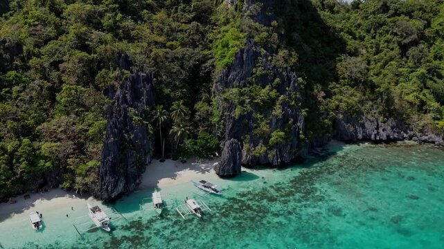 Aerial view of the iconic limestone cliffs at Entalula Beach in El Nido. Tropical scenery with traditional boats and white sand in Palawan, Philippines.