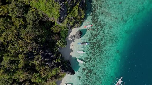 Stunning bird's eye view of Entalula Beach in El Nido. Traditional boats on crystal clear turquoise water and white sand in Palawan, Philippines.