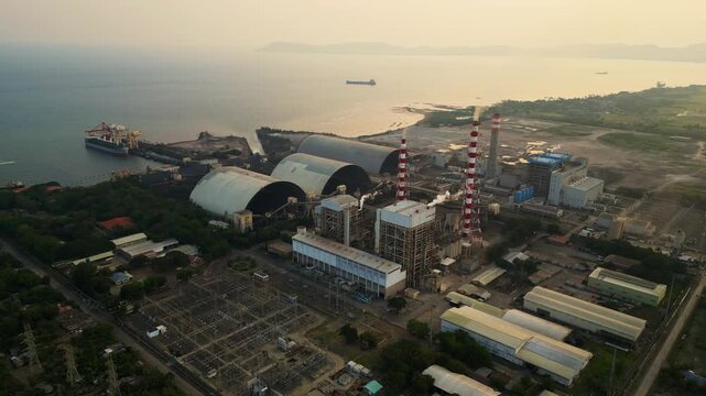 Calaca Powerplant Batangas Philippines &mdash; top aerial view of industrial power plant during sunset with smoke emissions and glowing dramatic sky.