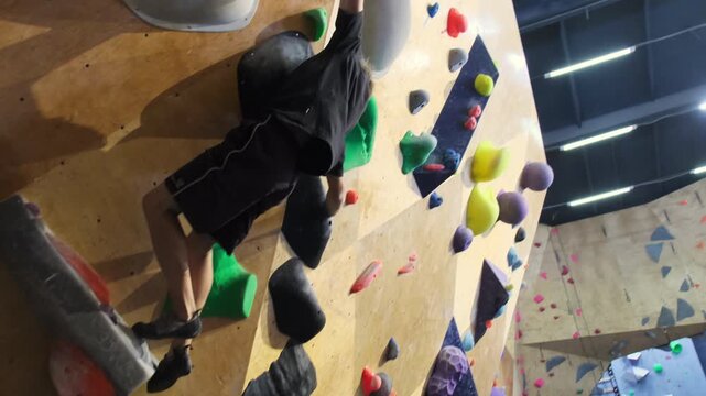 Sporty youngster navigates climbing surface gripping engineered steps. Agile teen surmounts climbing route slow motion
