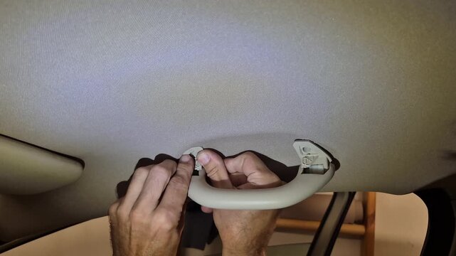Car grab handle removal, person working on vehicle interior headliner, auto maintenance project