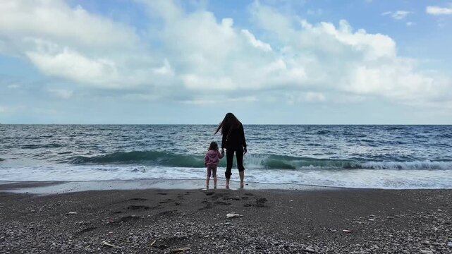 Mother and Daughter on the Beach Looking at the Sea Horizon