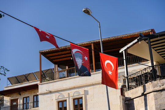 Turkish flags and portrait of Mustafa Kemal Ataturk hanging on on stone house on city street. National pride, cultural identity of Turkey , historical heritage concept, patriotism