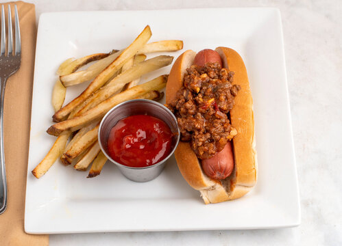 hot dog top with sloppy joe  and  a side of french fries