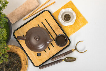 Naklejka premium Traditional Yixing teapot on bamboo chaban tray with tea leaves and cup. Chinese tea ceremony accessories for Zen meditation, relaxation and wellness. Healthy beverage ritual concept