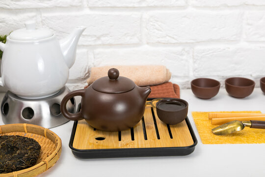 Clay teapot on wooden chaban tray for traditional Chinese tea ceremony. Puer tea leaves on bamboo sieve with ceramic cups. Healthy lifestyle, meditation and wellness concept