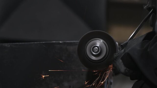 A stationary sharpening machine, grinding, sharpening, and metalworking in a garage workshop, manual work. The craftsman wears protective clothing, gloves, and goggles.