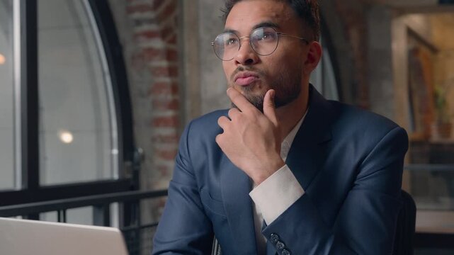 Arabian business man with laptop thinking businessman analyze solution job research brainstorming Indian thoughtful male guy worker agent working think idea pondering difficult question in office