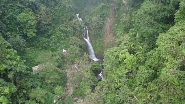 Video footage from a drone flying over a waterfall in Indonesia, the camera movement is backwards, can be used for video editing materials such as color grading.
