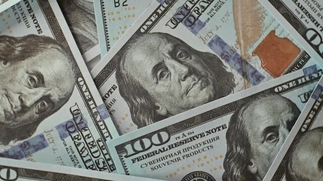 hundred dollar bills arranged in an overlapping pattern on a flat surface. This visually engaging setup emphasizes the theme of finance and wealth