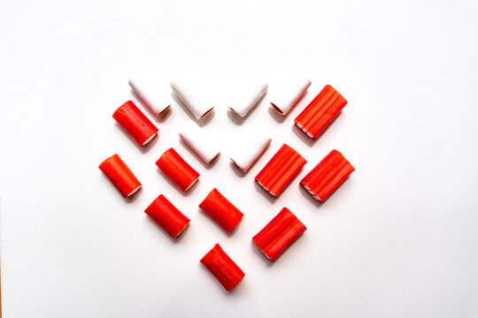 Red chewy candy pieces arranged in a geometric pattern on a white background. Smooth glossy texture create a playful sweet life concept of candy snacks, minimal food design and modern style.