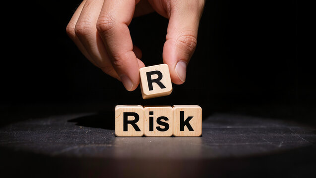 Hand Placing Letter Block to Spell 'Risk' on Dark Surface