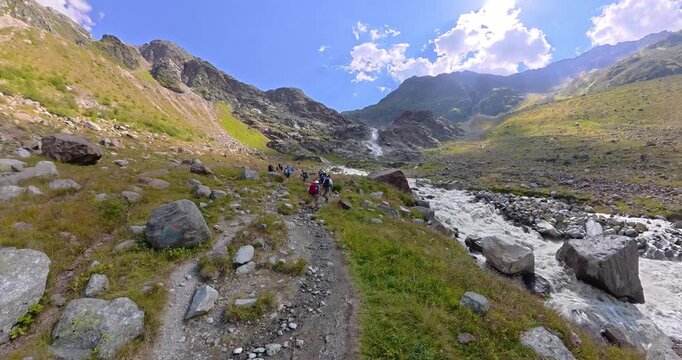 Hiking group ascending beside Pitztal waterfall in Alps Austria