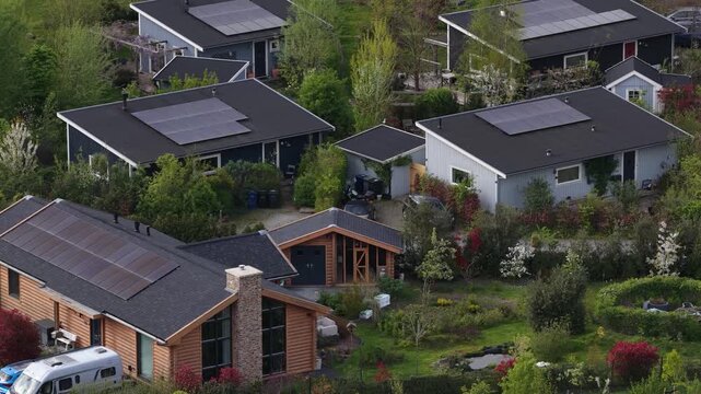 Aerial view of a modern eco friendly neighborhood with houses featuring rooftop solar panels and lush green gardens, showcasing sustainable living and renewable energy in a suburban community